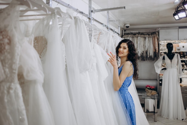 Hermosa chica elige un vestido de novia en el salón de bodas