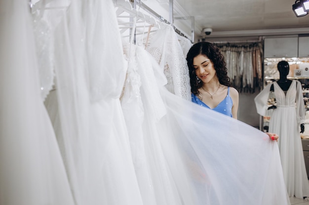 Hermosa chica elige un vestido de novia en el salón de bodas