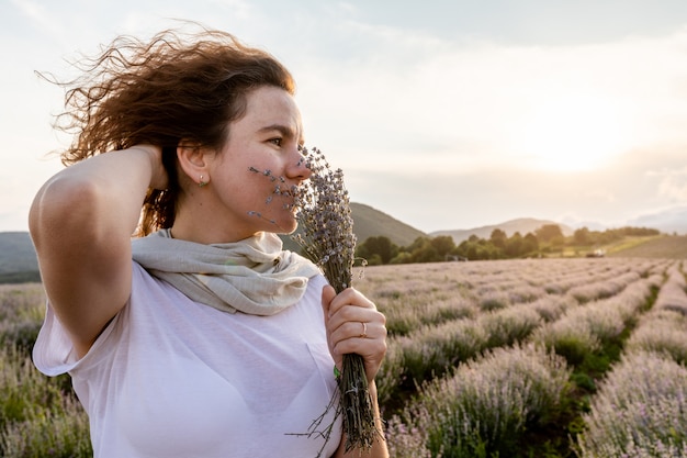 Hermosa chica se encuentra antes del atardecer y soñador huele lavanda