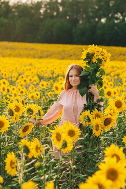 Hermosa chica en un enorme campo amarillo de girasoles.