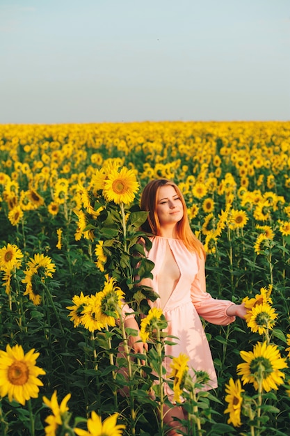 Hermosa chica en un enorme campo amarillo de girasoles.