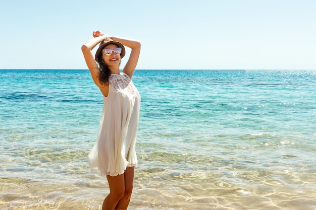 Hermosa chica está caminando por el mar en un día soleado de verano Tiempo de vacaciones