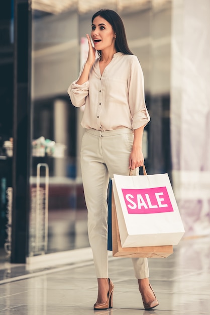 Hermosa chica está sosteniendo bolsas de compras