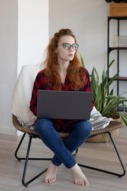 Hermosa chica está trabajando en una computadora portátil en casa
