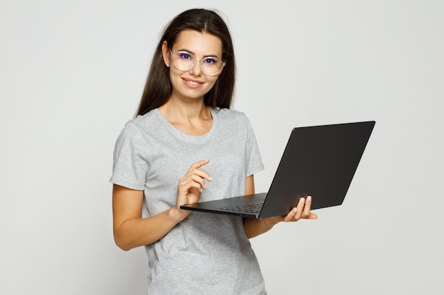 Foto hermosa chica estudiante en ropa casual y gafas trabajando en equipo portátil