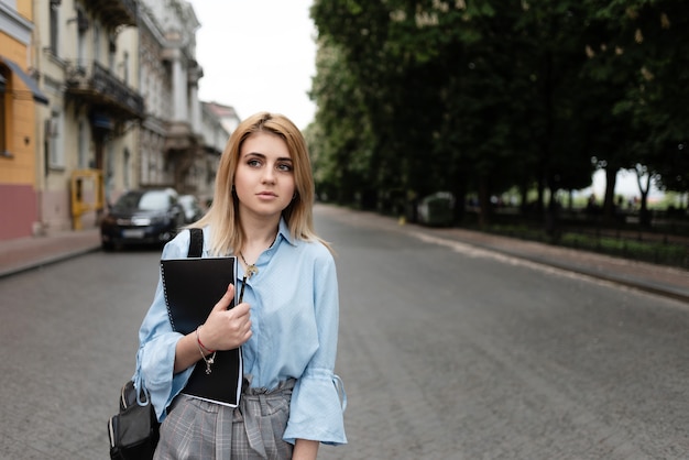 Hermosa chica estudiante rubia caminando por la ciudad