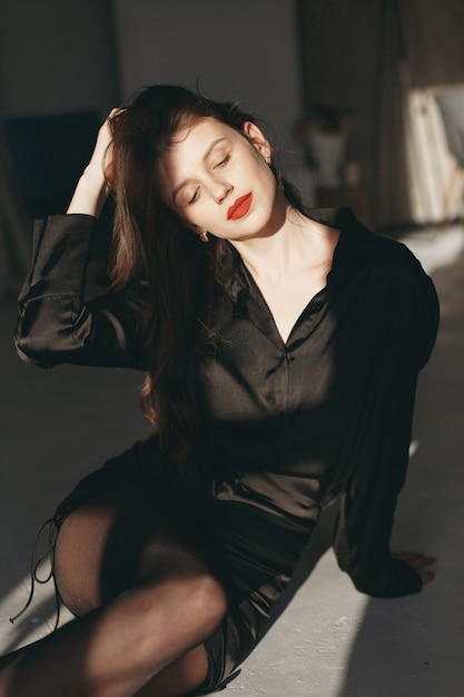 Hermosa chica en un estudio. Mujer elegante con un vestido negro.