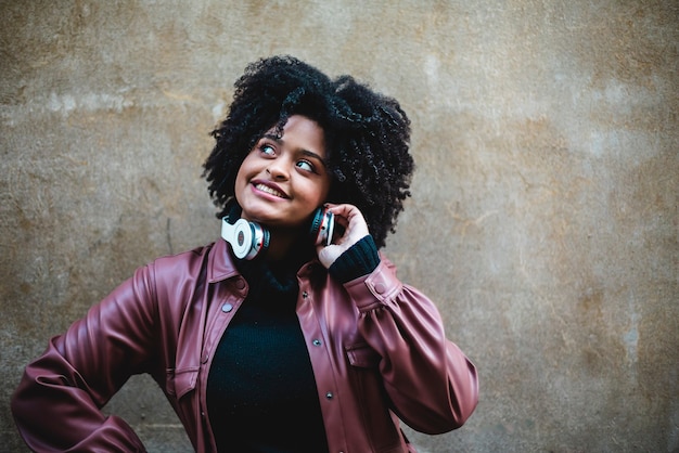 Hermosa chica de etnia negra escucha música con grandes auriculares blancos.