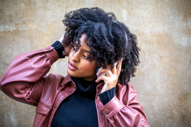 Hermosa chica de etnia negra escucha música con grandes auriculares blancos.