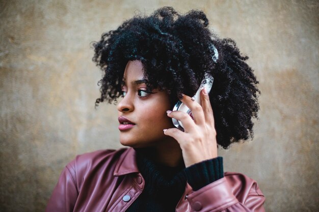 Hermosa chica de etnia negra escucha música con grandes auriculares blancos.