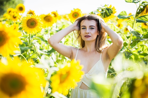 Hermosa chica europea con un vestido blanco en la naturaleza con girasoles