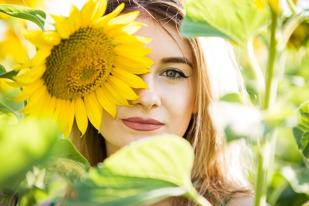 Hermosa chica europea con un vestido verde en la naturaleza con girasoles