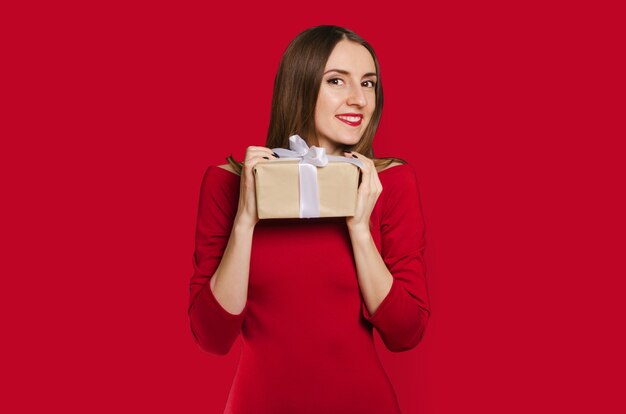 Hermosa chica feliz con caja de regalo en vestido rojo. Concepto de San Valentín