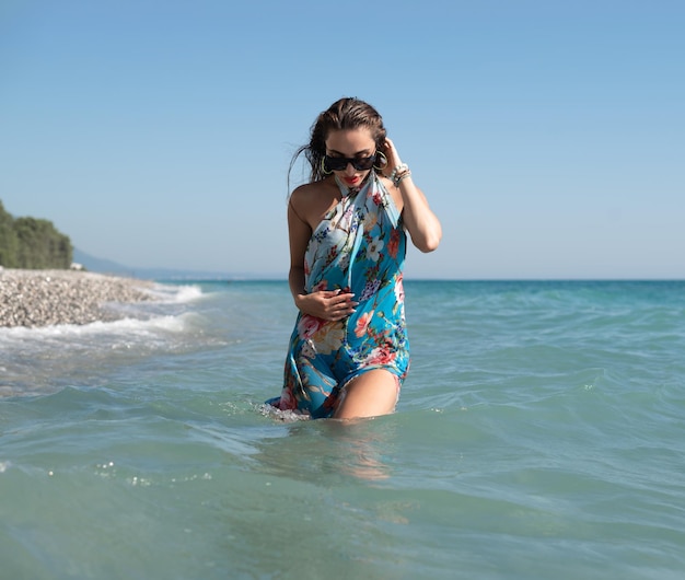 Hermosa chica feliz en el mar con ropa de verano brillante y elegante
