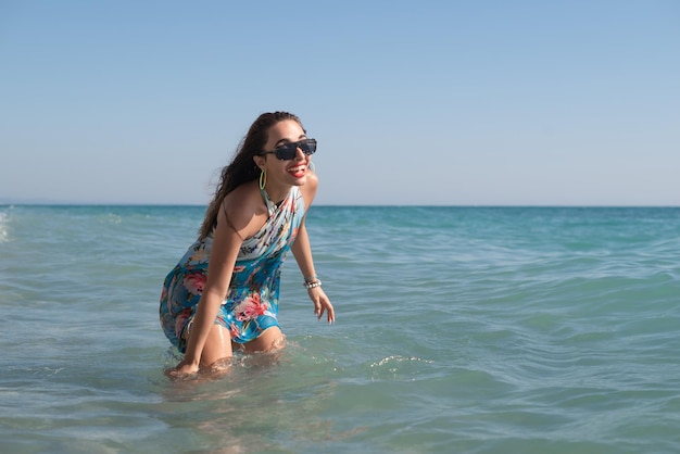 Hermosa chica feliz en el mar con ropa de verano brillante y elegante