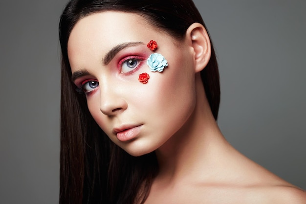 Hermosa chica con flores en la cara maquillaje colorido