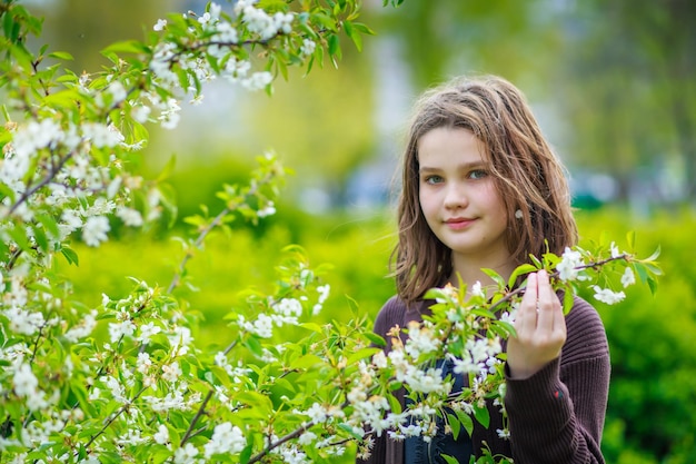 Hermosa chica entre flores de cerezo en primavera Retrato de una chica con cabello castaño y ojos verdes