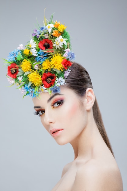 Hermosa chica con flores de colores de primavera en la cabeza