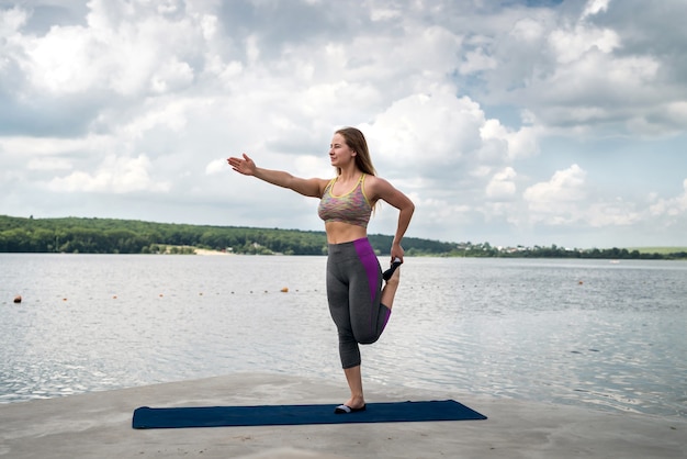 Hermosa chica en forma en ropa deportiva negra haciendo estiramientos y posturas de yoga