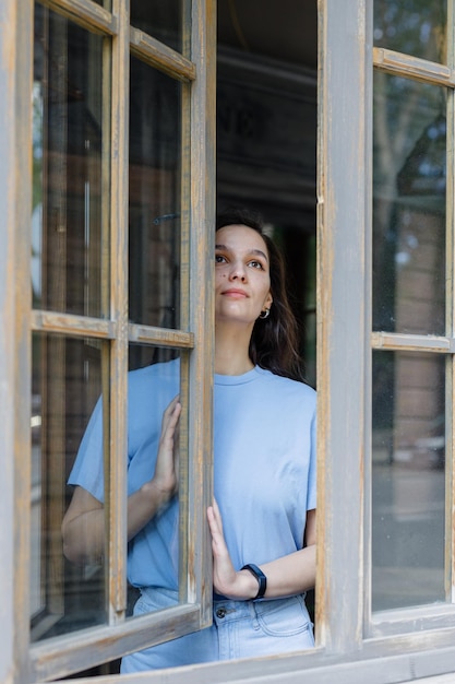 Hermosa chica frente a una ventana en una mañana en la ciudad