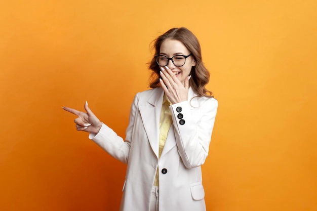 Hermosa chica con gafas y chaqueta blanca muestra sus manos a un lado y se burla de una mujer avergonzada