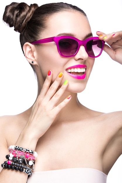 Hermosa chica con gafas de sol rosas con maquillaje brillante y uñas coloridas Cara de belleza