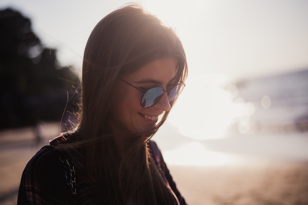 hermosa chica con gafas de sol sentado en la playa