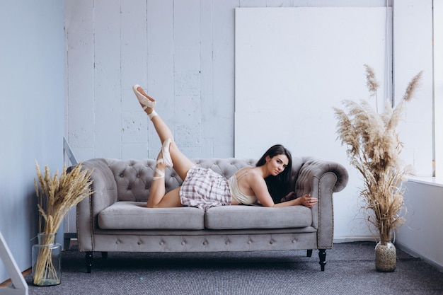 Hermosa chica gimnasta en casa realiza ejercicios en el sofá