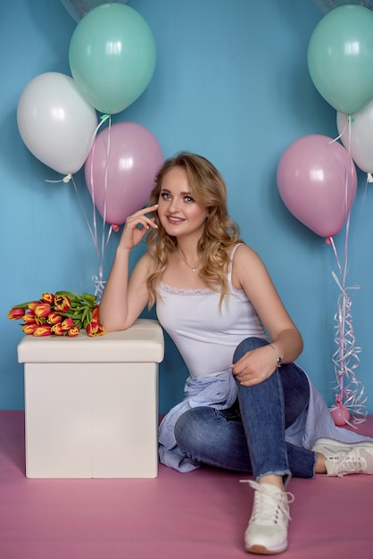 Hermosa chica con globos y un ramo de flores