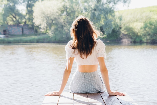 Hermosa chica en la glorieta en el lago