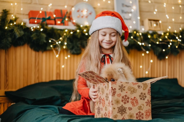 Hermosa chica con gorro de Papá Noel tiene un cachorro como regalo para Año Nuevo, magia navideña y milagro, los sueños se hacen realidad.
