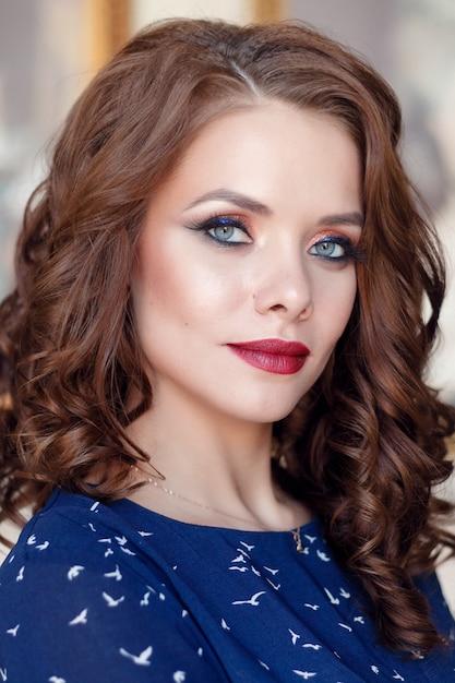 Hermosa chica guapa en vestido de cóctel azul vaina posando en el interior de la biblioteca de lujo. Retrato de moda joven modelo femenino