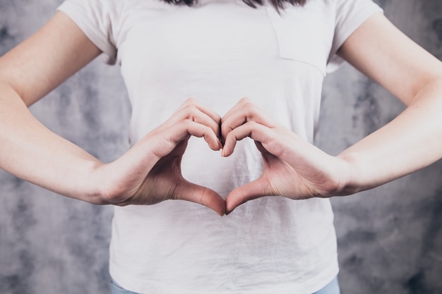 Hermosa chica hace un gesto de corazón con las manos