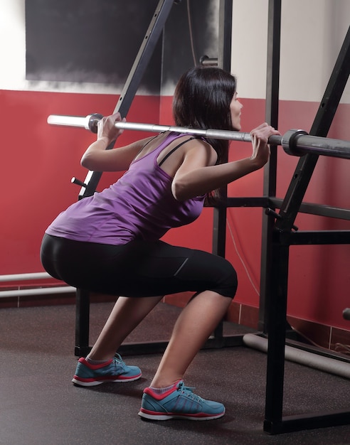 Hermosa chica haciendo ejercicios en el simulador en el gimnasio