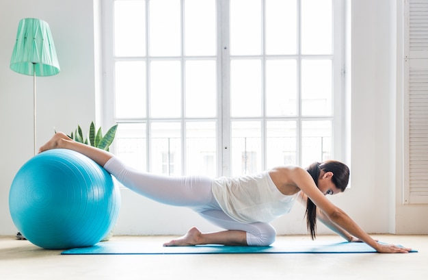 Hermosa chica haciendo entrenamiento y yoga en casa por la mañana