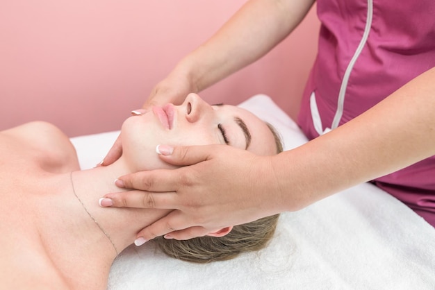 Hermosa chica haciendo masaje facial en clínica de belleza