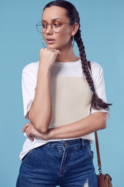 Hermosa chica hispana encantadora en camiseta blanca, jeans y gafas