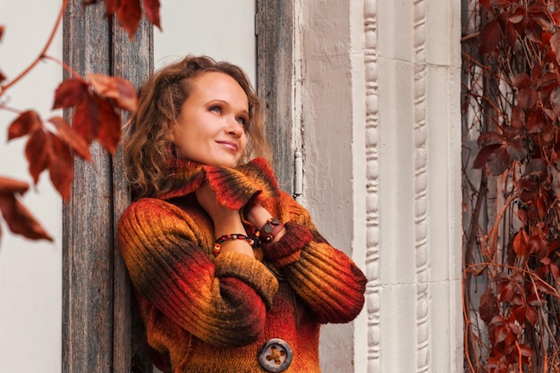 Foto hermosa chica en hojas de otoño y bajo el brillo del sol.