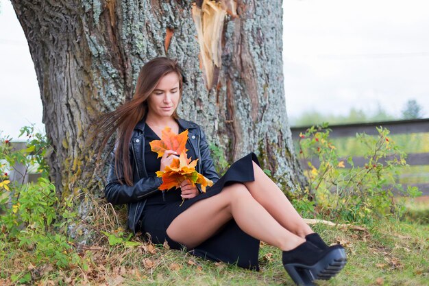 Hermosa chica en hojas de otoño