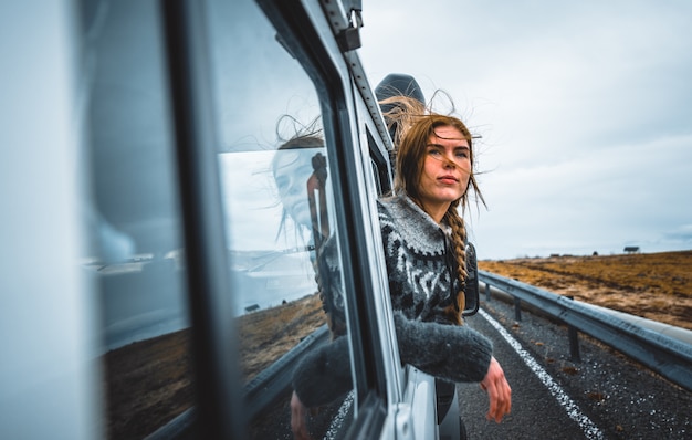 Hermosa chica islandesa disfrutando del paisaje en Islandia, mirando por la ventanilla del coche