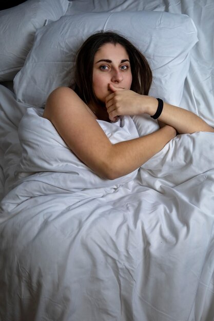 Foto hermosa chica joven en la cama con ropa de cama blanca