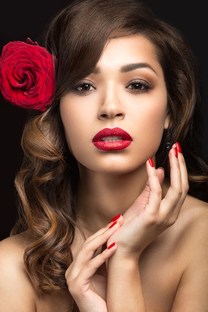 Hermosa chica con labios rojos y una rosa en el pelo.