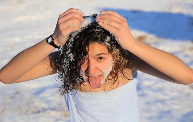 Hermosa chica se lava por la nieve en invierno
