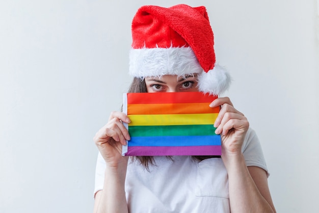 Hermosa chica lesbiana con sombrero rojo de Santa Claus con bandera arco iris LGBT aislada