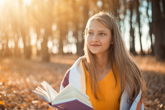 Hermosa chica leyendo un libro y soñando con algo positivo