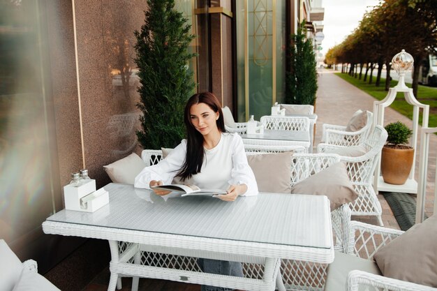 Una hermosa chica linda en un café bebe café en una mesa.