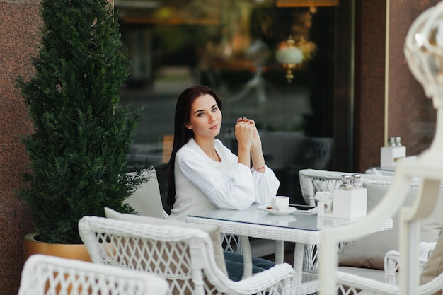 Una hermosa chica linda en un café bebe café en una mesa.