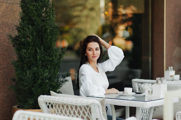 Una hermosa chica linda en un café bebe café en una mesa.