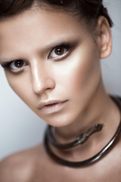 Hermosa chica con maquillaje de arte y decoración de cabello de moda en forma de cara de belleza de serpiente