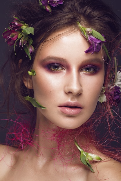 Hermosa chica con maquillaje artístico y flores.